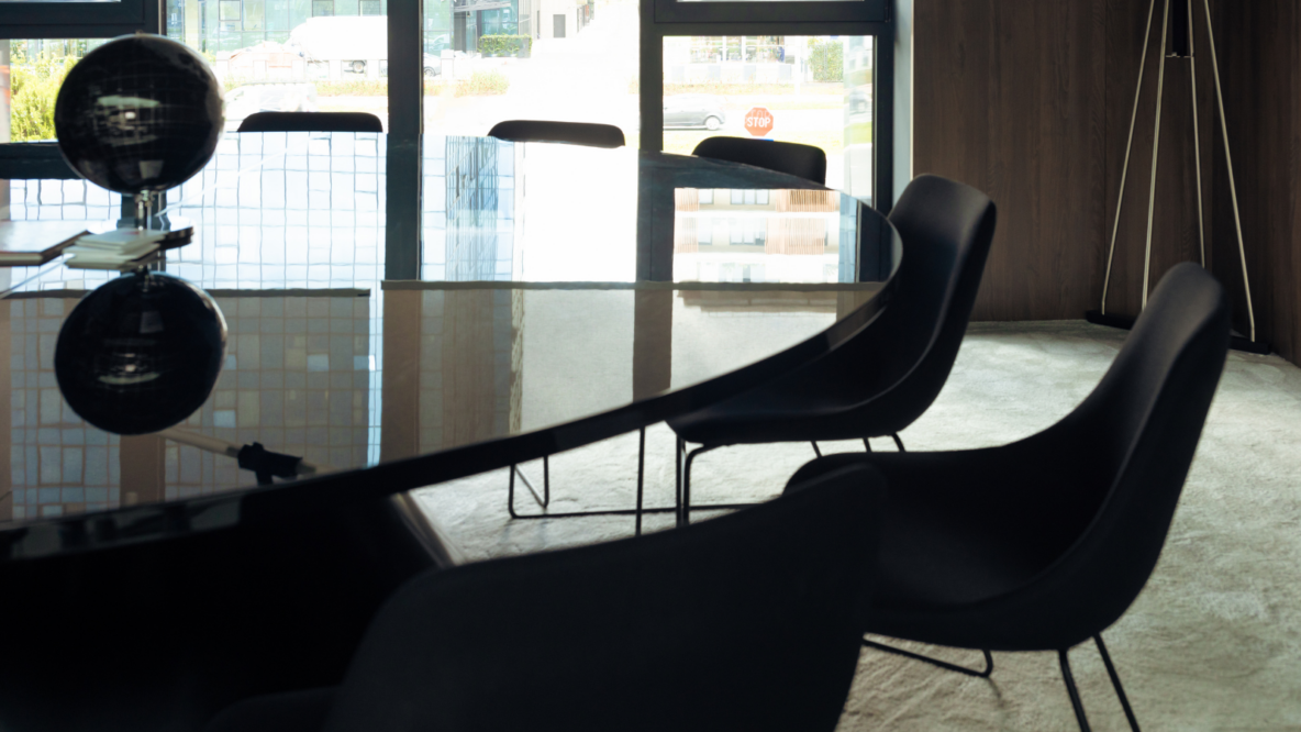 Row of chairs line up around glass table