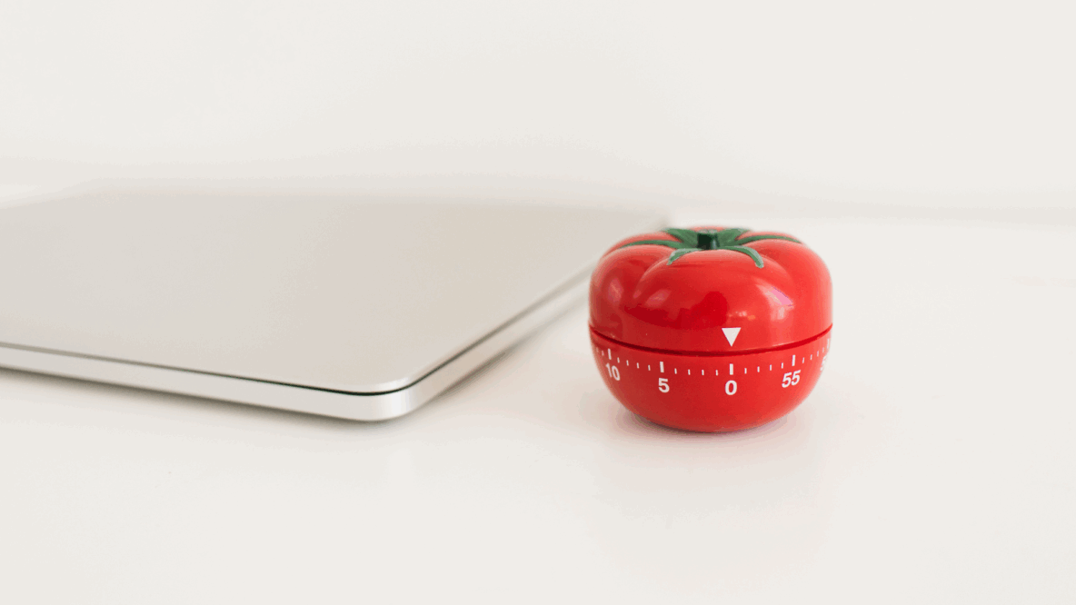 Red tomato timer next to laptop on table.png