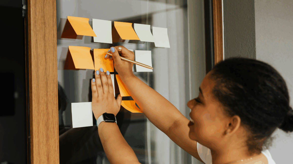 Woman writing on post it on window